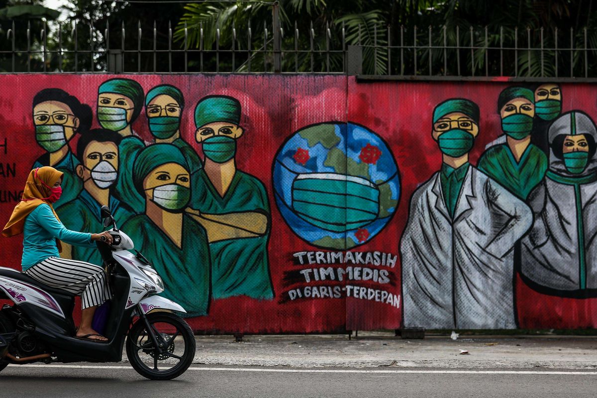 Warga menggunakan masker saat mengendarai sepeda motor melintas di depan mural tentang pandemi virus corona atau COVID-19 di Jalan Raya Jakarta-Bogor, Depok, Jawa Barat, Selasa (7/4/2020). Mural tersebut ditujukan sebagai bentuk dukungan kepada tenaga medis yang menjadi garda terdepan dalam menghadapi COVID-19 di Indonesia.