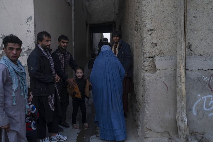 Seorang wanita mengenakan burka berjalan ke rumahnya di Kabul, Afghanistan, Minggu, 14 November 2021. 