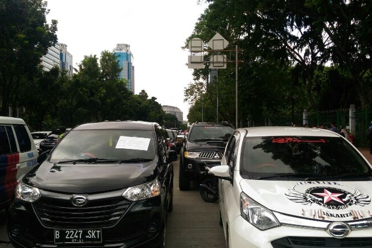 Mobil para pengemudi taksi online diparkir di dua lajur paling kiri Jalan Medan Merdeka Selatan dan menyebabkan macet, Senin (29/1/2018).