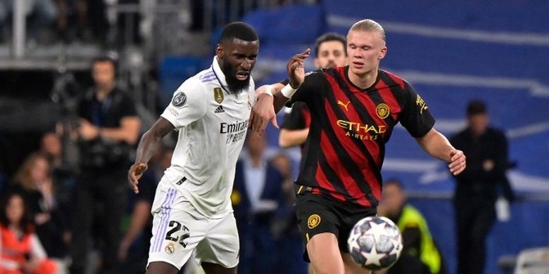 Striker Manchester City, Erling Haaland (kanan), berebut bola dengan bek tengah Real Madrid, Antonio Ruediger, dalam laga leg pertama semifinal Liga Champions 2022-2023. Laga Real Madrid vs Man City yang digelar di Stadion Santiago Bernabeu pada Selasa (9/5/2023) malam waktu setempat tersebut berakhir dengan skor imbang 1-1. (Foto oleh OSCAR DEL POZO / AFP)