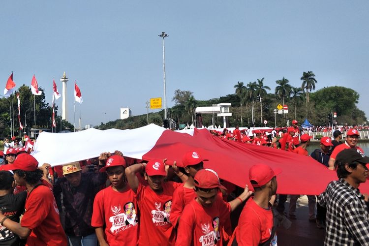 Relawan Joko Widodo-Maruf Amin membentangkan Bendera Merah Putih raksasa sepanjang 200 meter di kawasan Monas, Jakarta Pusat, Minggu (20/10/2019).