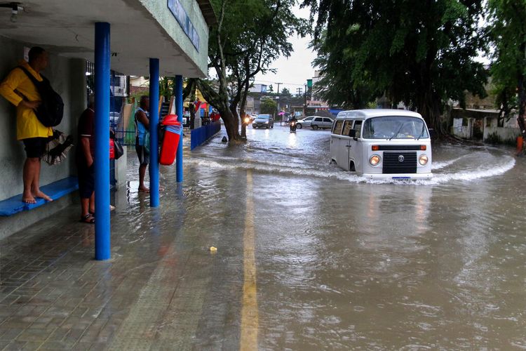 Sejumlah warga berada di halte bus saat pengemudi van Volkswagen menerjang jalan yang banjir di Recife, Begara Bagian Pernambuco, Brasil, Sabtu (28/5/2022).