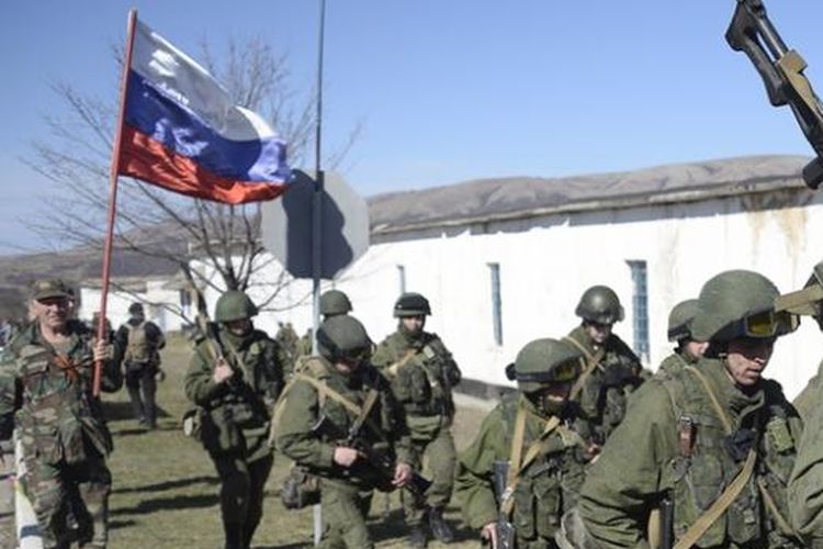 Seorang pria sambil membawa bendera Rusia menyambut rombongan pasukan bersenjata di desa Perevalne dekat ibu kota Crimea, Simferopol, Senin (3/3/2014).
