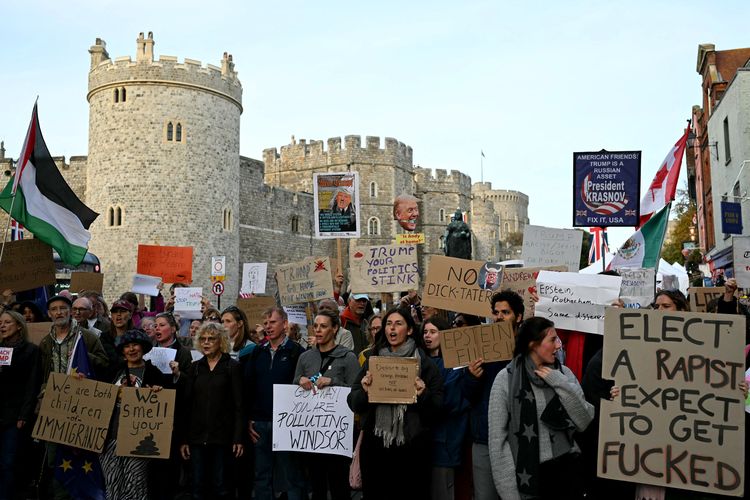 Para demonstran memegang poster protes selama kunjungan kenegaraan Presiden AS Donald Trump, di luar Kastil Windsor di Windsor pada 16 September 2025. Ribuan polisi, barikade baja, hingga larangan drone disiapkan Inggris untuk mengamankan kunjungan Trump di Kastel Windsor.