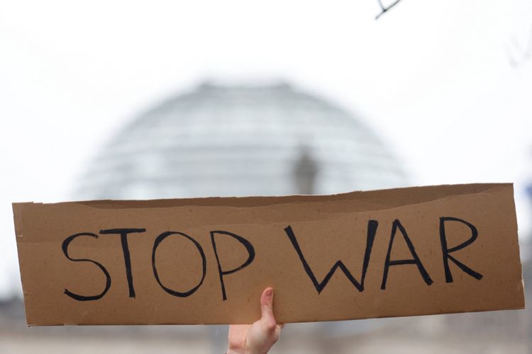 Pengunjuk rasa anti perang membawa papan bertuliskan 'hentikan perang' di depan kekanseliran Jerman, setelah Rusia meluncurkan operasi militer besar atas Ukraina di Berlin, Jerman, Jumat (25/2/2022).