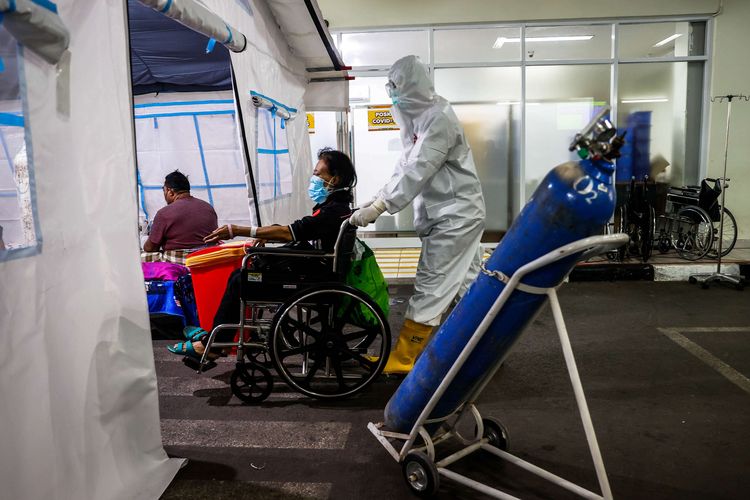 Petugas medis dengan mengenakan hazmat membawa pasien Covid-19 dengan kursi roda ke tenda darurat di depan instalasi gawat darurat (IGD) Rumah Sakit Umum Daerah (RSUD) Cengkareng, Jakarta Barat, Kamis (24/6/2021). Meningkatnya kasus Covid-19 di ibu kota dalam beberapa hari terakhir mengakibatkan penuhnya tingkat keterisian kamar perawatan di rumah sakit tersebut sehingga sebagian pasien Covid-19 terpaksa menempati tenda darurat.