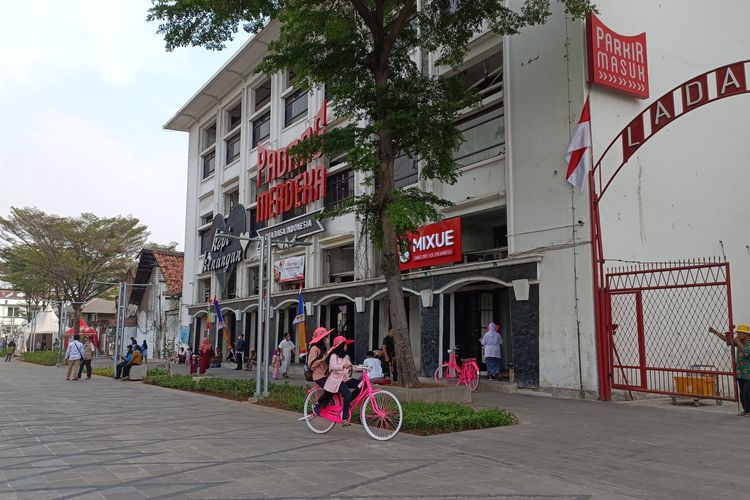 Warga beraktivitas di Jalan Lada dengan latar Gedung BNI dan Stasiun Jakarta Kota, Jumat (26/08/2022). Sebagai bagian dari revitalisasi kawasan Kota Tua, Jalan Lada turut diubah menjadi area pejalan kaki.