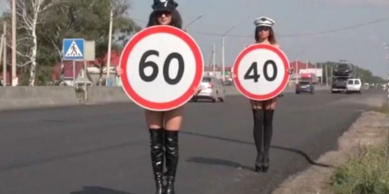 Para perempuan ini membawa rambu yang menunjukkan batas kecepatan maksimum untuk mengingatkan para pengemudi yang melintasi sebuah kawasan permukiman atau persimpangan yang ramai.