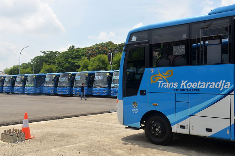 Seorang warga melintas di depan bus Trans Koetaradja di gudang terminal Batoh, Banda Aceh, Aceh, Senin (30/3/2020). Pemerintah Aceh menggudangkan seluruh armada angkutan kota Trans Kuetaradja sejak Jumat (27/3/2020) hingga batas belum ditentukan untuk mencegah penyebaran COVID-19.