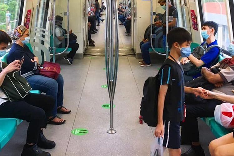 Di tengah pandemi virus corona, warga Singapura memakai masker dan duduk berjarak minimal 1 kursi kosong ketika menggunakan Mass Rapid Transit (MRT) Singapura jalur Timur-Barat atau warna hijau di kawasan Queenstown, Minggu sore (19/04/2020)