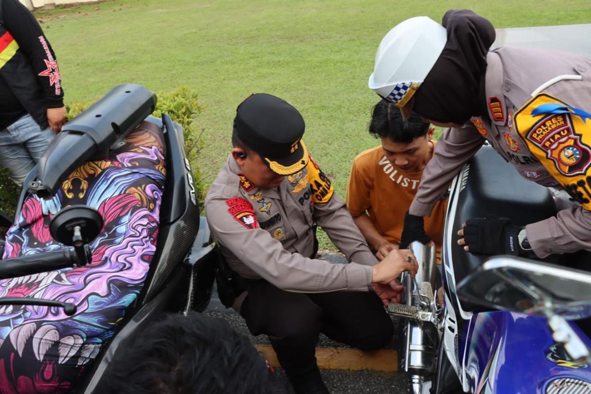 Kapolres Pelalawan AKBP Suwinto bersama Kasatlantas AKP Akira Ceria, saat melepas knalpot brong dari salah satu sepeda motor milik pemuda, di Kabupaten Pelalawan, Riau, Minggu (17/3/2024).