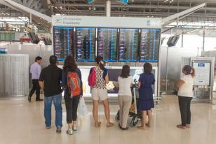 Penumpang melihat papan pengumuman penerbangan di Bandara Suvarnabhumi, Bangkok, Thailand. 