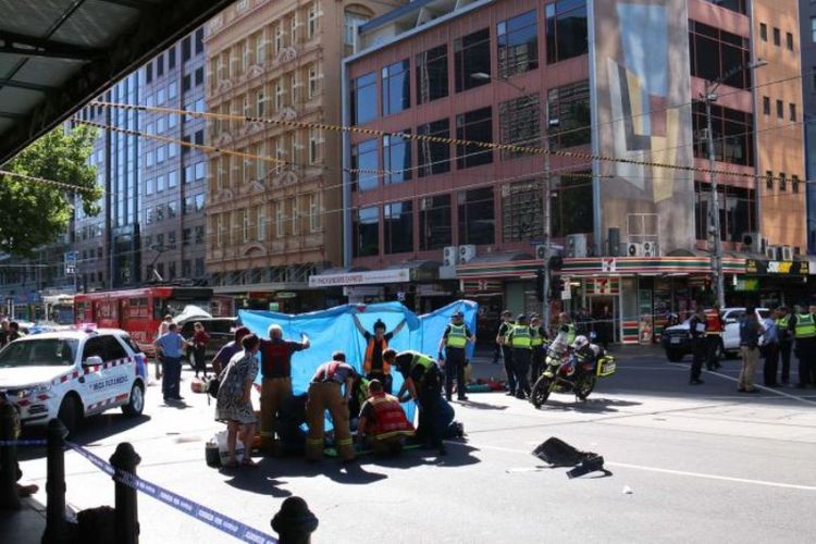 Petugas paramedis menangani para korban yang tertabrak di depan Stasiun Flinders Street. (ABC News/Gus Goswell)
