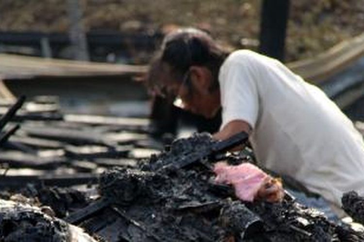 Asmaniar (38), salah seorang pemulung menjerit histeris saat mengumpulkan puing-puing sisa kebakaran rumah berkontruksi kayu miliknya di Desa Mon Geudong, Kecamatan Banda Sakti, Lhokseumawe, Senin (3/8/2015) 