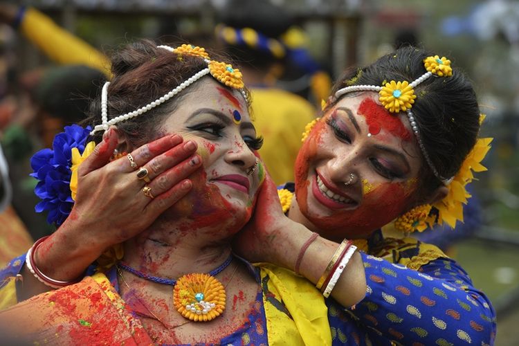 Penduduk di India mengolesi temannya dengan bubuk berwarna selama perayaan festival Holi di Siliguri, Kamis (1/3/2018). (AFP/Diptendu Dutta).