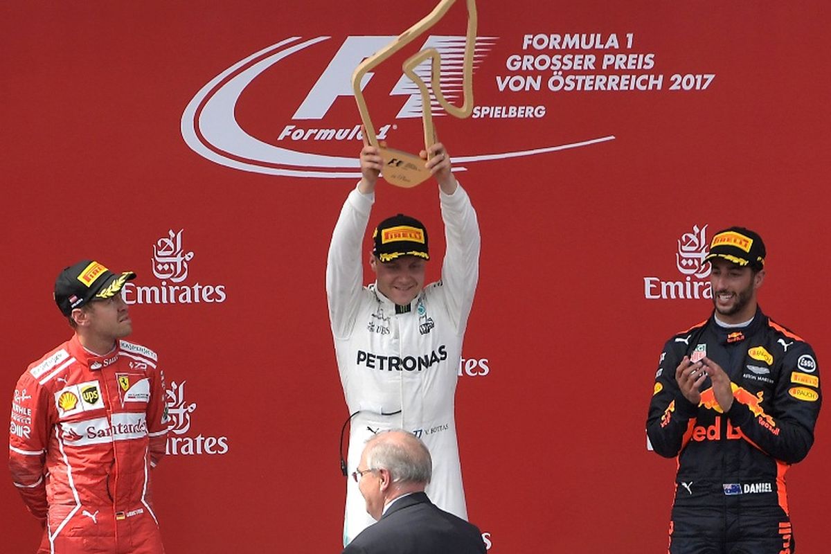Pebalap Mercedes, Valtteri Bottas (tengah), mengangkat trofi kemenangannya pada balapan GP Austria di Red Bull Ring, Spielberg, Austria, Minggu (9/7/2017).