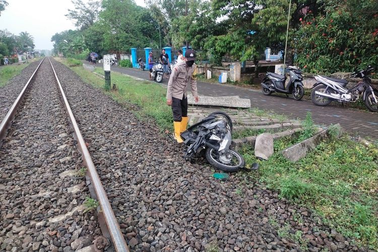 Anggota polisi saat mengevakuasi sepeda motor korban yang tertabrak kereta api saat melintasi perlintasan kereta api tanpa palang pintu, Minggu (26/3/2023).