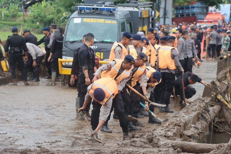 Anggota Polda Bali saat membersihkan Jalan Raya Denpasar Gilimanuk yang tertutup lumpur akibat banjir pada Senin (17/10/2022). /Polda Bali