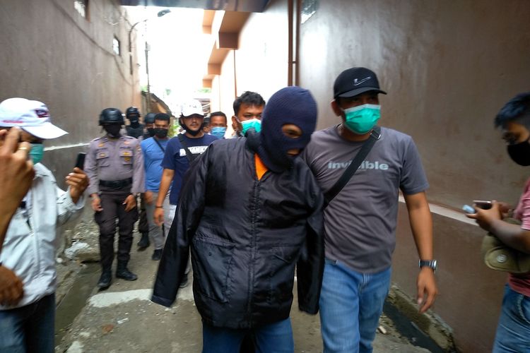 Rahmadsyah, tersangka pelaku pembunuhan kepada 2 anak tirinya berinisial IF (10) dan RA (5) digelandang petugas saat pra rekonstruksi. Pelaku membunuh kedua anak tirinya di rumah kontrakannya kemudian membuang jenazahnya ke sebuah parit di lorong sempit antara gedung sekolah Global dan rumah warga pada Jumat (19/6/2020).