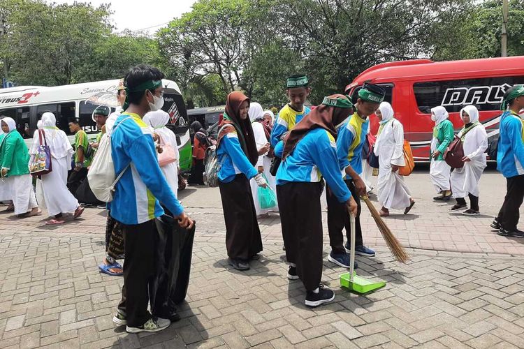 Pelajar bersih-bersih sampah di sekitar GOR Sidoarjo saat acara puncak 1 Abad NU, Selasa (7/2/2023).