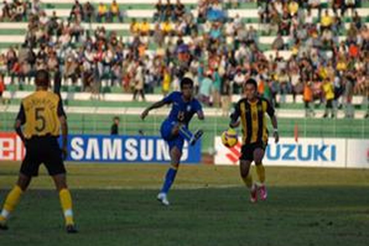Pemain Thailand (biru) melepaskan tendangan, dan dua pemain Malaysia hanya bisa melihat. Dalam laga ini, Thailand menang 3-0.
