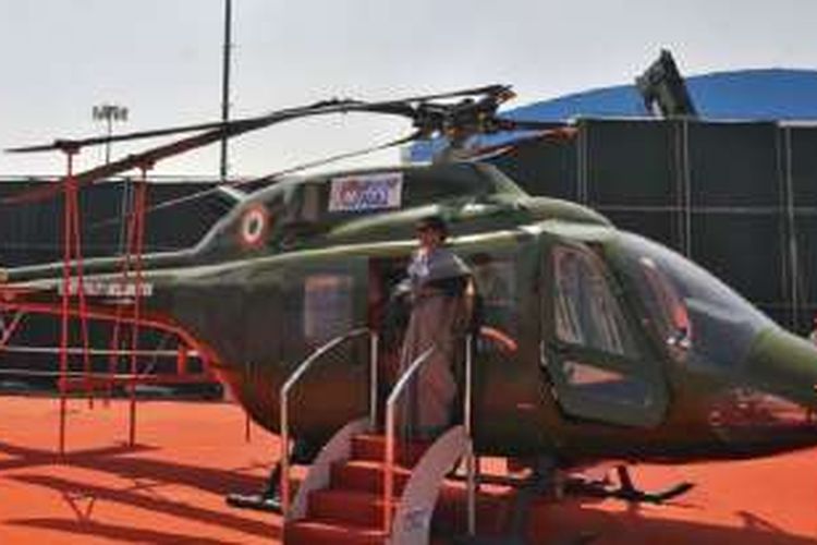 Seorang perempuan berpose di depan helikopter milik Angkatan Udara India (IAF) di bandara militer Yelahanka, Bengaluru. 