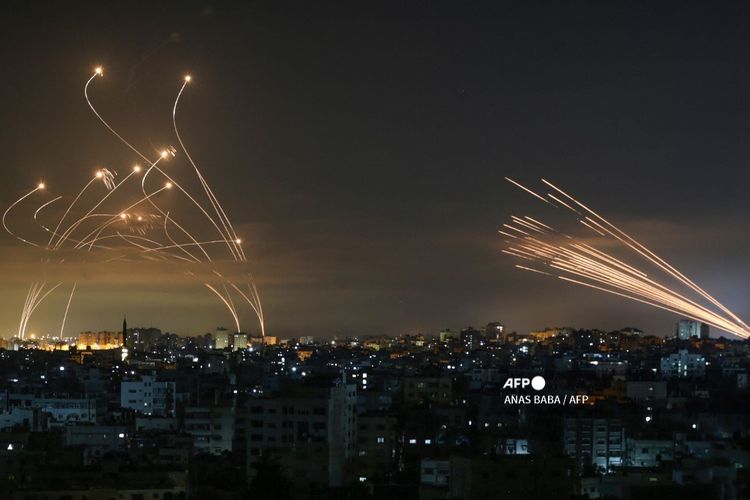 Sistem pertahanan rudal Iron Dome Israel (kiri) mencegat roket (kanan) yang ditembakkan oleh gerakan Hamas menuju Israel selatan dari Beit Lahia di Jalur Gaza utara seperti yang terlihat di langit di atas Jalur Gaza pada 14 Mei 2021