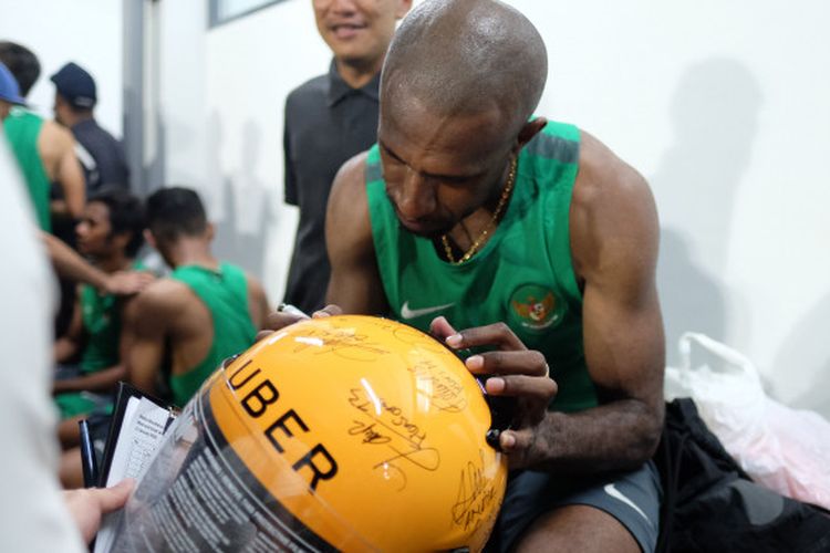 Pemain Timnas Indonesia Selection Boaz Salosa membubuhkan tanda tangan di helm Uber usai menjalani latihan di Lapangan ABC, Kompleks Gelora Bung Karno, Jumat (12/1/2018).