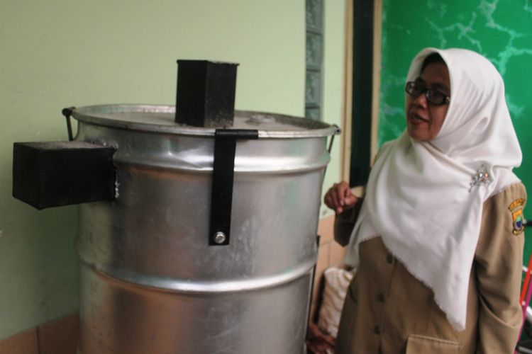 Nenden Raspati, perempuan paruh baya asal Cianjur, Jawa Barat bersama alat daur ulang sampah yang dibuatnya yang diberi nama tabung Reaktor 120C.