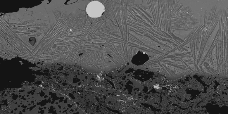 Gambar mikroskop menunjukkan bongkahan terak baja tahan karat yang tertanam.
