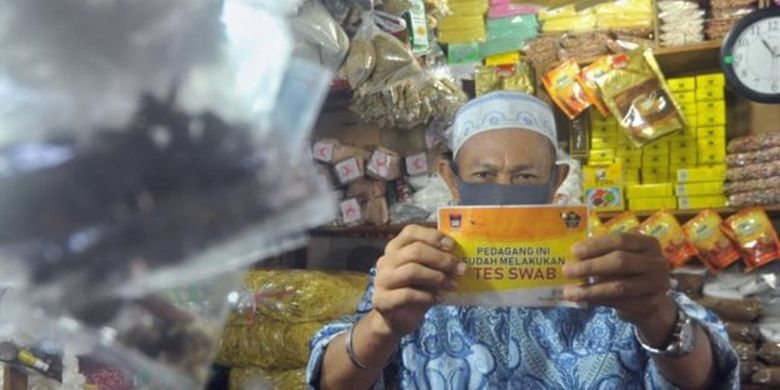 Pedagang menunjukan stiker tanda sudah melakukan tes swab dan negatif COVID-19, di Pasar Raya Padang, Sumatera Barat, Jumat (05/06) 