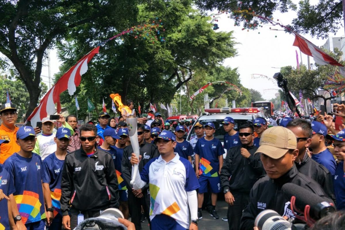 Mantan atlet layar Kusdiana Adi berlari membawa obor Asian Games saat prosesi torch relay atau pawai obor di Jalan Raya Rawa Bambu, Jakarta Selatan, Rabu (15/8/2018).