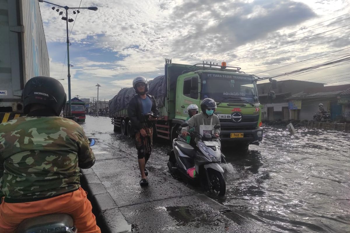 Salah seorang pengemudi terpaksa mendorong motornya yang mogok akibat banjir rob di Pantura Sayung, Kabupaten Demak, Jumat (23/5/2025).
