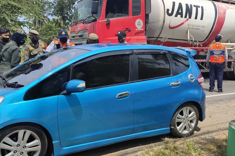 Aparat memeriksa kendaraan berpenumpang di jalur provinsi di wilayah Kapanewon Temon, Kabupaten Kulon Progo, Daerah Istimewa Yogyakarta. Kebijakan peniadaan mudik membuat banyak kendaraan mengangkut pemudik terpaksa harus putar balik.