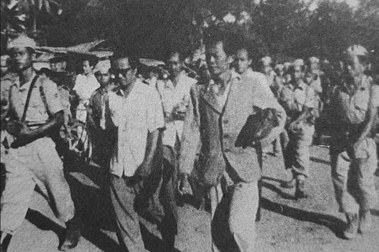 Mantan Perdana Menteri Indonesia Amir Sjarifuddin dikawal oleh anggota militer Indonesia yang telah merincinya setelah peristiwa Madiun 1948