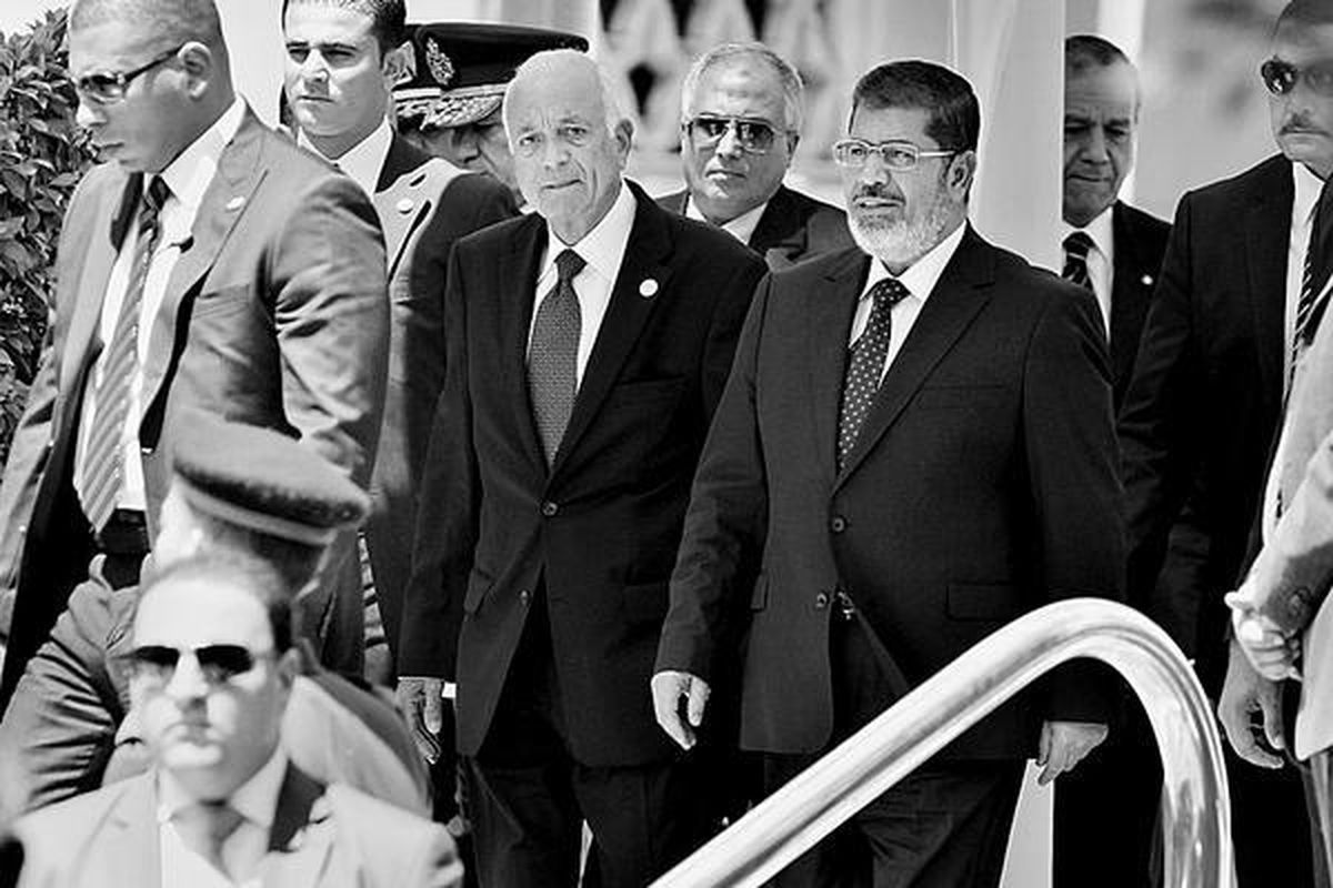 Pengawal mengelilingi Presiden Mesir Muhammad Mursi (kanan) dan Sekretaris Jenderal Liga Arab Nabil Elaraby, yang berjalan bersisian saat meninggalkan markas Liga Arab di Kairo, Mesir, Rabu (5/9). Mursi mengatakan, Presiden Suriah Bashar al-Assad harus belajar dari sejarah baru-baru ini dan mundur sebelum terlambat.