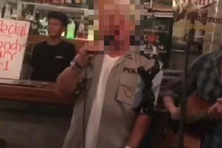 Seorang WN AS terlihat bernyanyi di sebuah cafe menggunakan seragam polisi. 