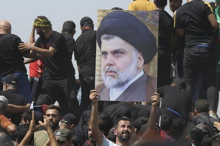 Seorang pengunjuk rasa memegang poster yang menggambarkan ulama Syiah Muqtada al-Sadr di jembatan menuju kawasan Zona Hijau di Baghdad, Irak, Sabtu, 30 Juli 2022. 