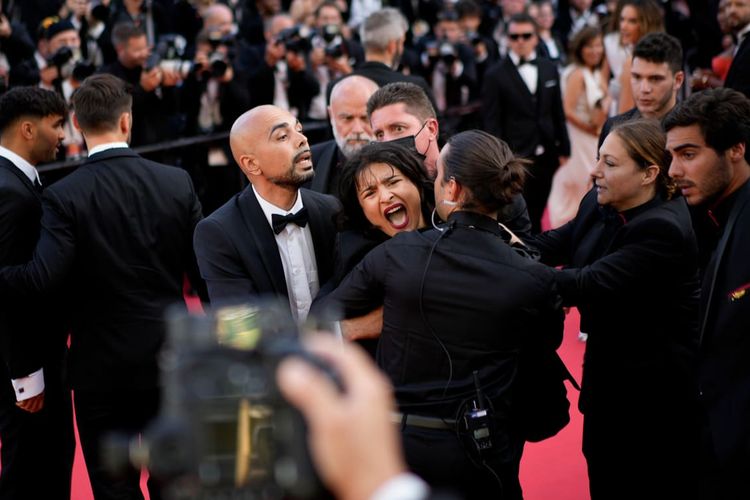 Seorang pengunjuk rasa bertelanjang dada dengan cat biru dan kuning di dada dan perutnya kedapatan berlari ke karpet merah di Festival Film Cannes pada Jumat (20/5/2022), memprotes kekerasan seksual di Ukraina.