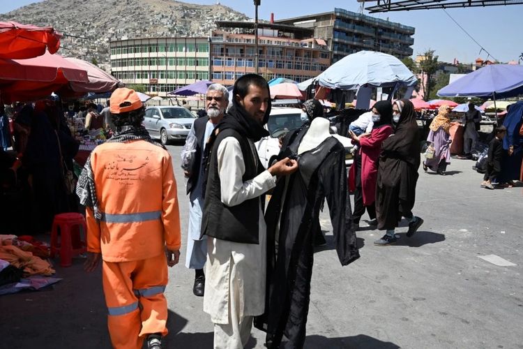 Orang-orang berjalan di sepanjang pasar di pusat kota Kabul pada 28 Agustus 2021, setelah militer Taliban mengambil alih Afghanistan. 