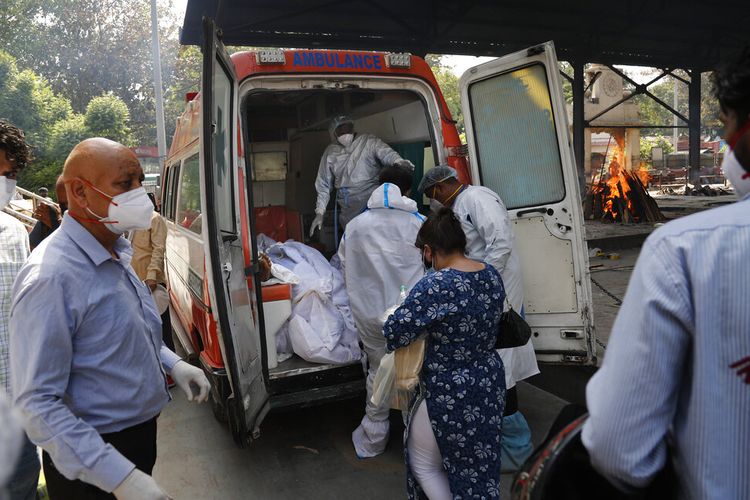 Petugas kesehatan bersiap untuk mengambil dari jenazah ambulans enam orang yang meninggal karena Covid-19 untuk dikremasi, di New Delhi, India, Senin (19/4/2021). 