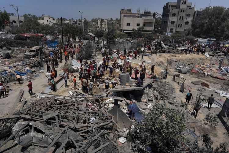 Warga Palestina melihat puing-puing tenda yang hancur dan membangun kembali rumah-rumah mereka setelah serangan militer Israel ke kamp al-Mawasi untuk para pengungsi internal (IDP), di dekat kota Khan Younis, Jalur Gaza selatan pada 13 Juli 2024, yang menewaskan 71 orang. Al-Mawasi telah dinyatakan sebagai zona aman oleh Israel, tetapi serangan tetap lancarkan di wilayah tersebut.