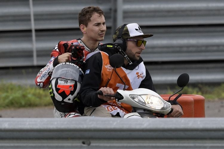 Pebalap Ducati Team asal Spanyol, Jorge Lorenzo, dibonceng salah satu marshal setelah terjatuh di tikungan 1 saat balapan GP Argentina di Autodromo Termas de Rio Hondo, Minggu (9/4/2017).