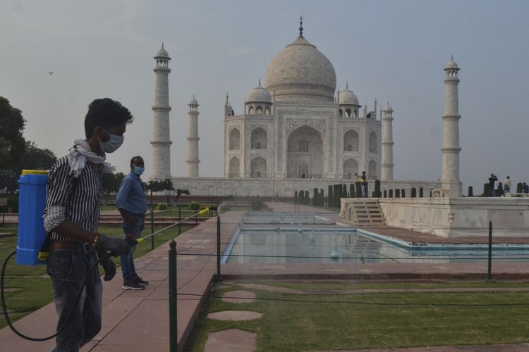 Seorang pria menyemprotkan desinfektan kawasan Taj Mahal yang dibuka kembali setelah ditutup lebih dari enam bulan akibat pandemi virus corona di Agra, India, Senin (21/9/2020).