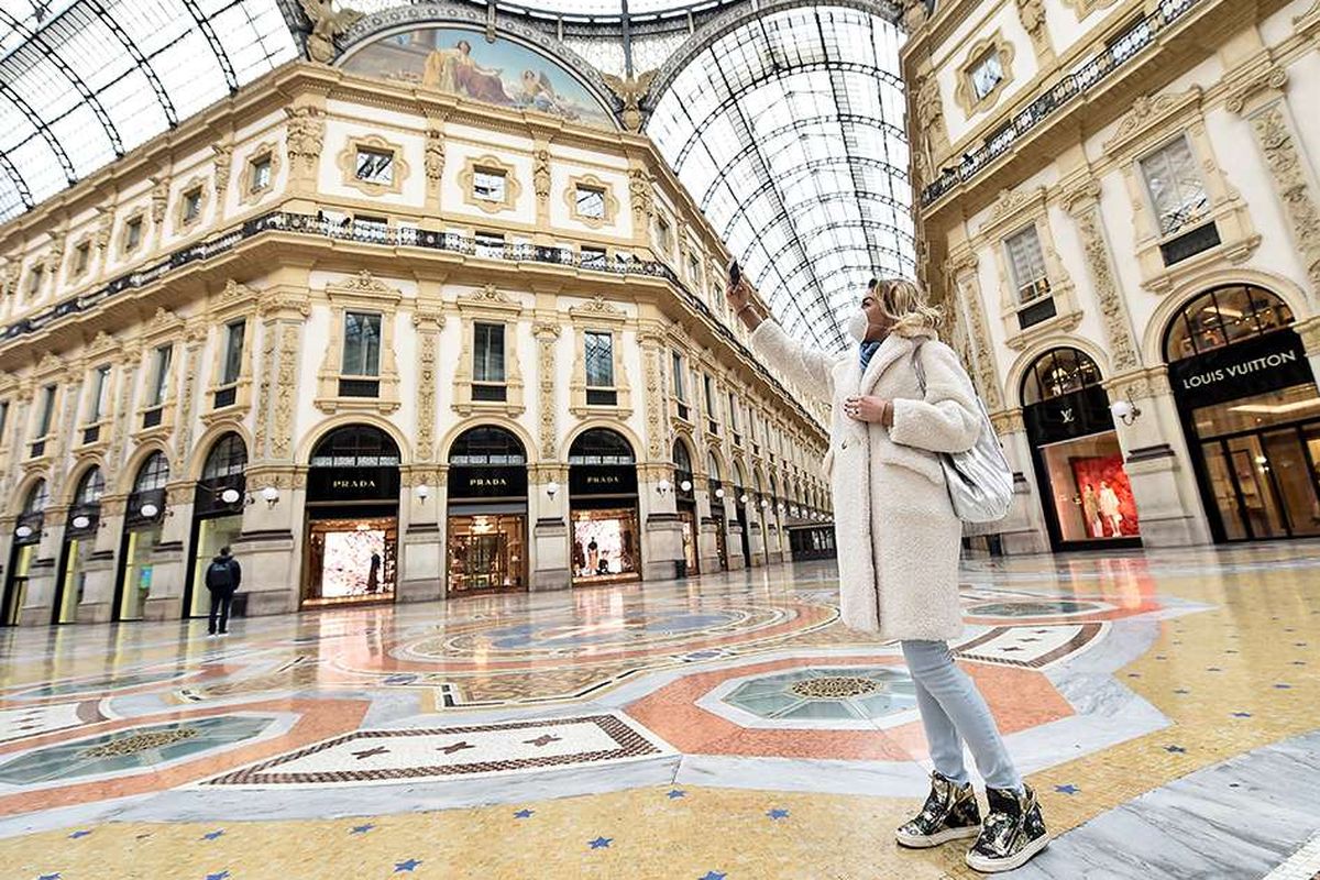 Seorang wanita memakai masker wajah saat berswafoto di Galleria Vittorio Emanuele II setelah dekrit yang memerintahkan seluruh Italia untuk ditutup sebagai tindakan keras yang belum pernah terjadi sebelumnya untuk mencegah penyebaran virus COVID-19, di Milan, Italia, Selasa (10/3/2020). Kian merajalelanya virus corona (COVID-19) membuat sejumlah kawasan di berbagai belahan dunia yang selama ini dikenal ramai seketika berubah menjadi sepi.