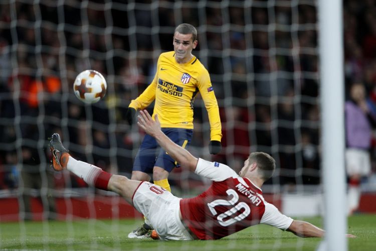 Antoine Griezmann melepas tendangan lebih cepat dari upaya Shkodran Mustafi memotong arah bola saat Atletico Madrid bermain imbang melawan Arsenal pada semifinal pertama Liga Europa, Kamis (26/4/2018).