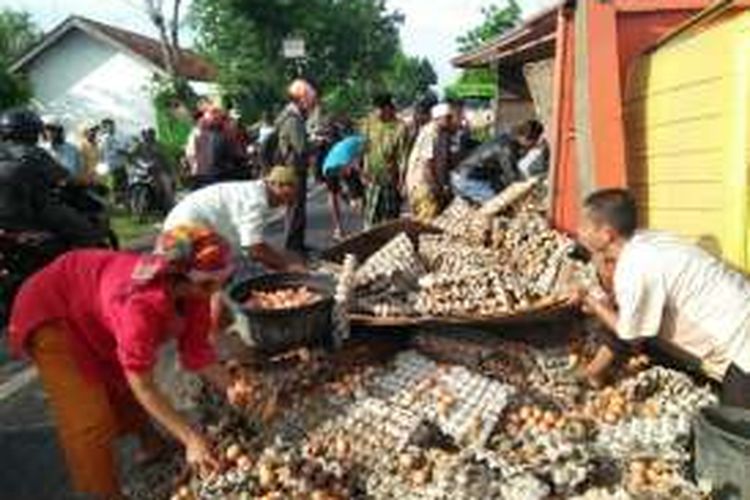 Warga rebutan telur yang diangkut truk karena mengalami kecelakaan di Desa Larangan Tokol, Kecamatan Tlanakan, Pamekasan, Rabu (7/12/2016).
