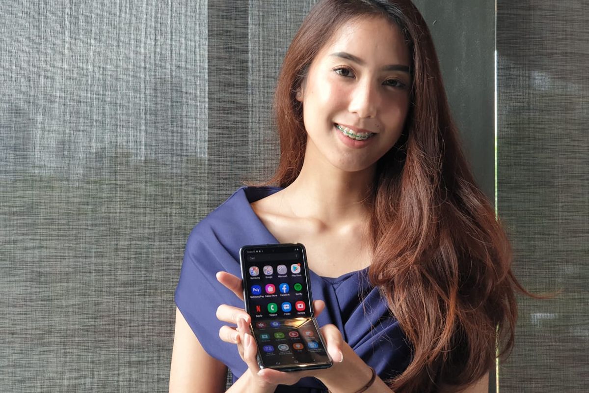 Seorang model menggenggam Galaxy Z Flip.