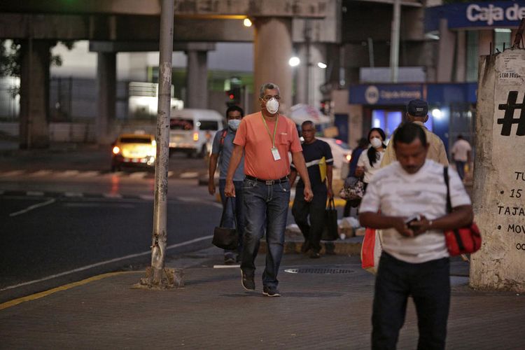 Pejalan kaki melintas di trotoar Panama City, Panama, 25 Maret 2020. Pemerintah menerapkan karantina mulai 25 Maret, yang membatasi warganya hanya boleh keluar rumah selama 2 jam untuk melakukan kewajiban pokok, dan jadwal keluar rumah digilir berdasarkan nomor kartu identitas.