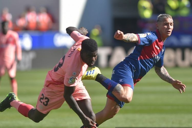 Bek Barcelona, Samuel Umtiti (kiri), berebut bola dengan penyerang SD Huesca, Chimy Avila, dalam laga Liga Spanyol SD Huesca vs FC Barcelona di Stadion El Alcoraz, Huesca, pada Sabtu (13/4/2019).  